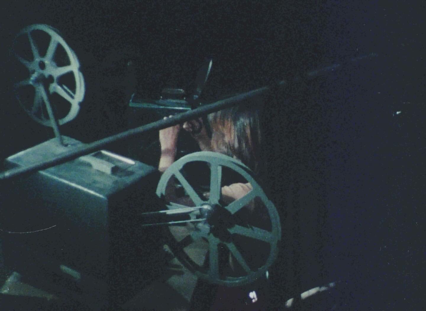 Dark image showing a person behind a 16mm film projector