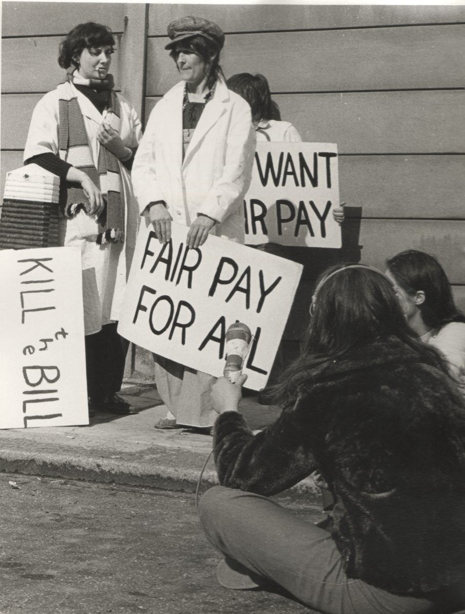 Black and white photograph of women holding signs reading 'fair pay for all'